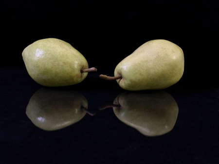 Green ripe pear on a black background. Bera pear variety, large fruits. Autumn fruits of a fruit tree.の写真素材