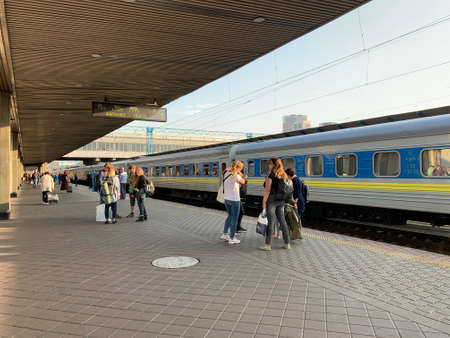 People on the platform of the station are waiting for the train. Men and women meet an approaching...
