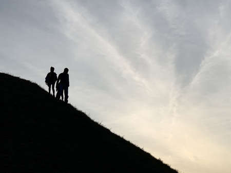 Silhouette of people on the top of the mountain. The family comes down the mountain. Silhouettes of...