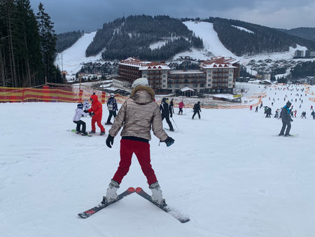 The girl learns to ski. A woman descends from the mountain in the snow. The skier goes downhill skiing. Transcarpathian region, Ukraine, Bukovel ski resort, January 13, 2021のeditorial素材