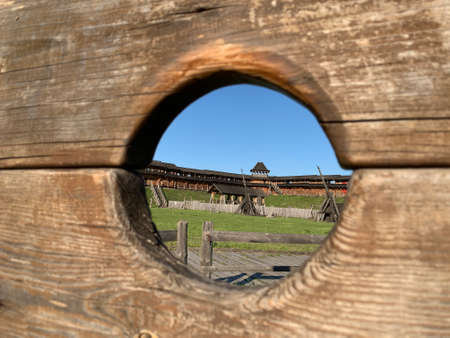Medieval wooden structure with a hole, revealing a view of a historical site.の写真素材