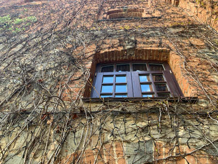 Window in the brick wall of the castle. Window opening in a medieval building. Wall with a window in...