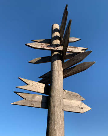 Wooden post with many pointers against the sky. There are different signs at the crossroads. There is a signpost for travelers at the crossroads.の写真素材