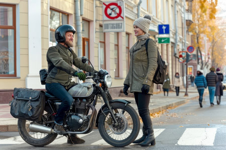 A man sits on his motorcycle, conversing with a woman who stands beside him in a casual setting.の素材