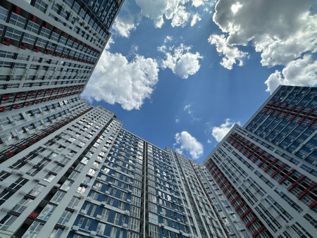 In the background is a blue sky with clouds, creating a contrast with the high-rise buildings. A...
