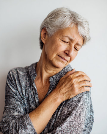Portrait of an elderly woman suffering from pain in the shoulder.の素材