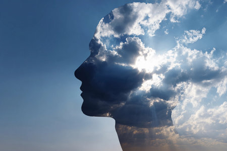 Creative silhouette of a human profile infused with clouds and sunlight above a clear sky representing imagination and dreamsの素材