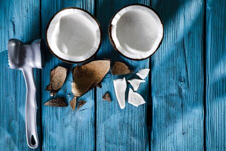 A coconut cut into halves on a wooden top board.