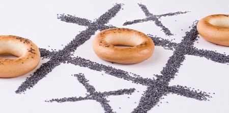 A tic-tac-toe game with bagels and poppy-seed. Close-up.