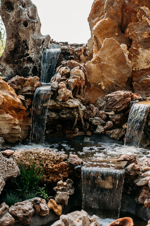 decorative waterfall in the Park with stones. A cozy place with an artificial waterfall in the Park.の写真素材