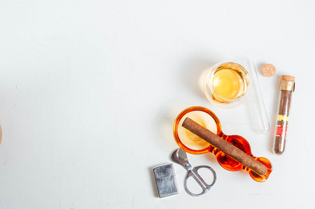 cigar, ashtray, cigarette scissors, lighter whiskey glass white concrete table.の写真素材