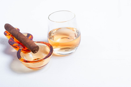cigar, ashtray, cigarette scissors, lighter whiskey glass white concrete table.の写真素材