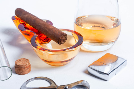 cigar, ashtray, cigarette scissors, lighter whiskey glass white concrete table.