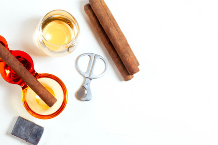 cigar, ashtray, cigarette scissors, lighter whiskey glass white concrete table. Smoke drink Scotch...