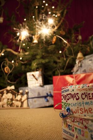 Boxes and betlehem under sparkling Christmas tree の写真素材