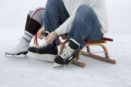 Skater preparing for skating - wearing skates sitting on sledgeの写真素材