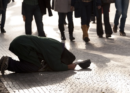 Beggar kneeling on a pavement with capのeditorial素材