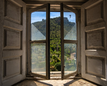 A dark old rural window opens to the bright green countrysideの写真素材