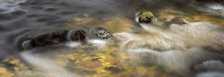 Long exposure with a rock in the colorful riverbed with water flowing 3の写真素材