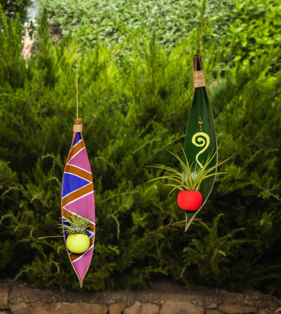 Colorful hanging ornaments with a small plant on them on a green background of vegetationの写真素材