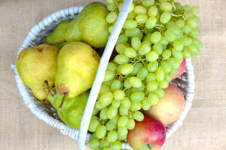 Apples, pears, grapes, peaches, plums from fresh harvest in a white wicker basket.の写真素材