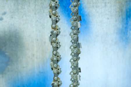 Chainsaw blade chain close-up on the background of the old wall in the garage.