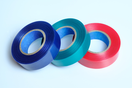 Three rolls of multicolored insulation tape. Isolated on blue background. Blue. Green. Red.の写真素材