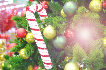 Decorated Christmas tree closeup. Santas cane, red and golden balls and illuminated garland with flashlights. New Year baubles macro photo with bokeh. Winter holiday light decoration.の写真素材