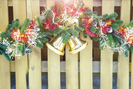 Christmas decoration. Christmas bells on a wreath of fir branches decorated with a garland with light bulbs and fir cones Winter holiday light decoration.の写真素材