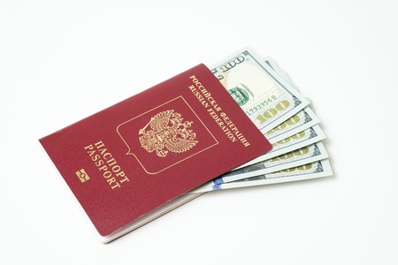 Biometric travel passport of the Russian Federation with dollars isolated on white background. Five bills for a hundred dollars. The concept of tourism. The concept of investment. Closeup.の写真素材