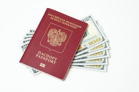 Biometric travel passport of the Russian Federation with dollars isolated on white background. Five bills for a hundred dollars. The concept of tourism. The concept of investment. Closeup.の写真素材