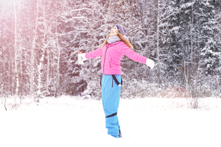 Beautiful happy laughing red-haired young woman in a winter tracksuit covered in snow flakes. Winter forest landscape background.の写真素材