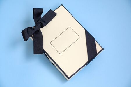 Gift box with colored ribbon as a gift for Christmas, New Year, Mothers Day, anniversary, birthday, party, isolated on a blue background, top view. Gift to a colleague at workの写真素材