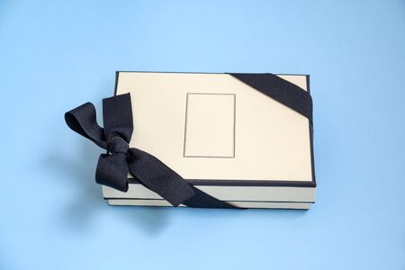 Gift box with colored ribbon as a gift for Christmas, New Year, Mothers Day, anniversary, birthday, party, isolated on a blue background, top view. Gift to a colleague at workの写真素材