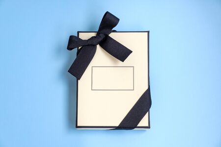 Gift box with colored ribbon as a gift for Christmas, New Year, Mothers Day, anniversary, birthday, party, isolated on a blue background, top view. Gift to a colleague at workの写真素材
