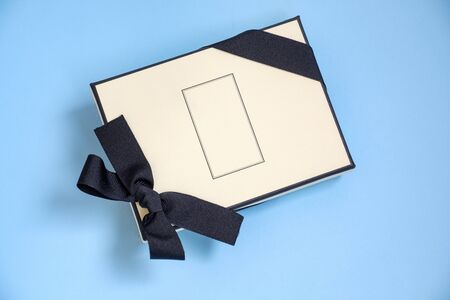 Gift box with colored ribbon as a gift for Christmas, New Year, Mothers Day, anniversary, birthday, party, isolated on a blue background, top view. Gift to a colleague at workの写真素材