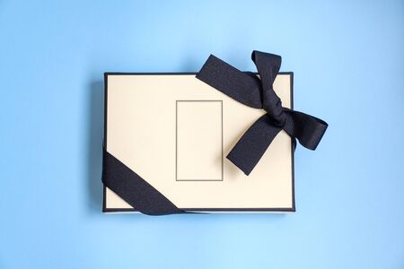 Gift box with colored ribbon as a gift for Christmas, New Year, Mothers Day, anniversary, birthday, party, isolated on a blue background, top view. Gift to a colleague at workの写真素材