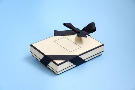 Gift box with colored ribbon as a gift for Christmas, New Year, Mothers Day, anniversary, birthday, party, isolated on a blue background, top view. Gift to a colleague at workの写真素材