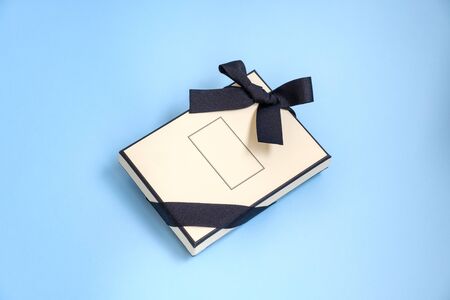Gift box with colored ribbon as a gift for Christmas, New Year, Mothers Day, anniversary, birthday, party, isolated on a blue background, top view. Gift to a colleague at workの写真素材