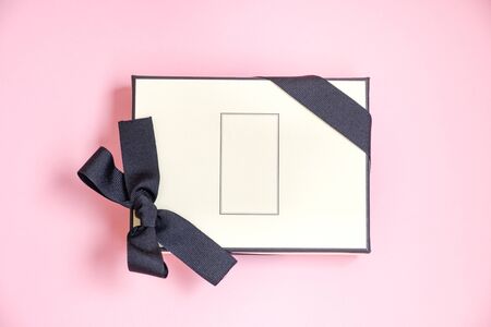 Gift box with colored ribbon as a gift for Christmas, New Year, Mothers Day, anniversary, birthday, party, isolated on a pink background, top view. Gift to a colleague at workの写真素材
