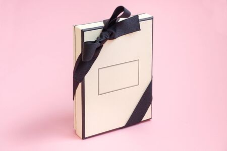 Gift box with colored ribbon as a gift for Christmas, New Year, Mothers Day, anniversary, birthday, party, isolated on a pink background, top view. Gift to a colleague at workの写真素材