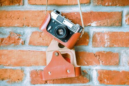 Vintage analog film camera with lens on a brick wall background.の写真素材