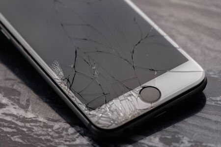 Broken and cracked smartphone screen. A broken smartphone lies on the table before repairing and replacing the monitor. Broken matrix.の写真素材