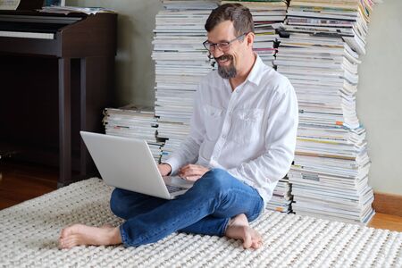 Male architect in a white shirt works at a laptop, smiling. Sits on the floor.の写真素材