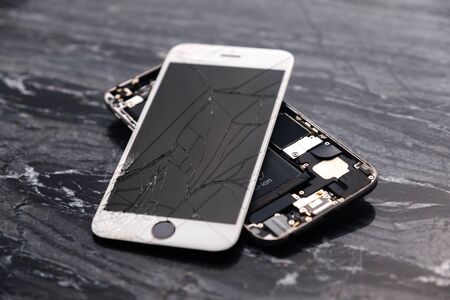 Broken and cracked smartphone screen. A broken smartphone lies on the table before repairing and replacing the monitor. Broken matrix.の写真素材