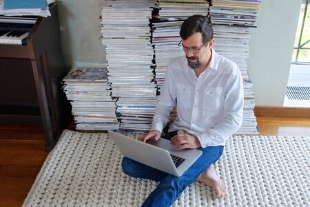 Male architect in a white shirt works at a laptop, smiling. Sits on the floor.の写真素材