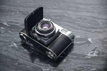 RUSSIA, MOSCOW - September 02, 2019: Vintage analog film camera with a lens and a charged film on a marble stone backgroundのeditorial素材