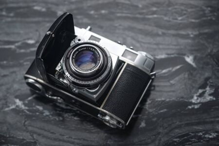 RUSSIA, MOSCOW - September 02, 2019: Vintage analog film camera with a lens and a charged film on a marble stone backgroundのeditorial素材