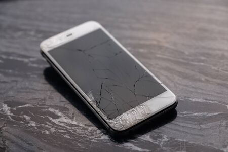 Broken and cracked smartphone screen. A broken smartphone lies on the table before repairing and replacing the monitor. Broken matrix. Close-up.の写真素材