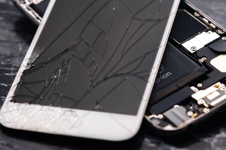 Broken and cracked smartphone screen. A broken smartphone lies on the table before repairing and replacing the monitor. Broken matrix. Close-up.の写真素材